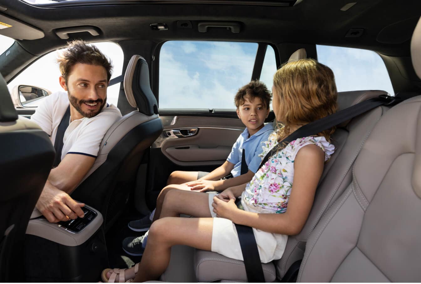 Interior cabin view of a Volvo XC90 showing children in the second row talking with their father.