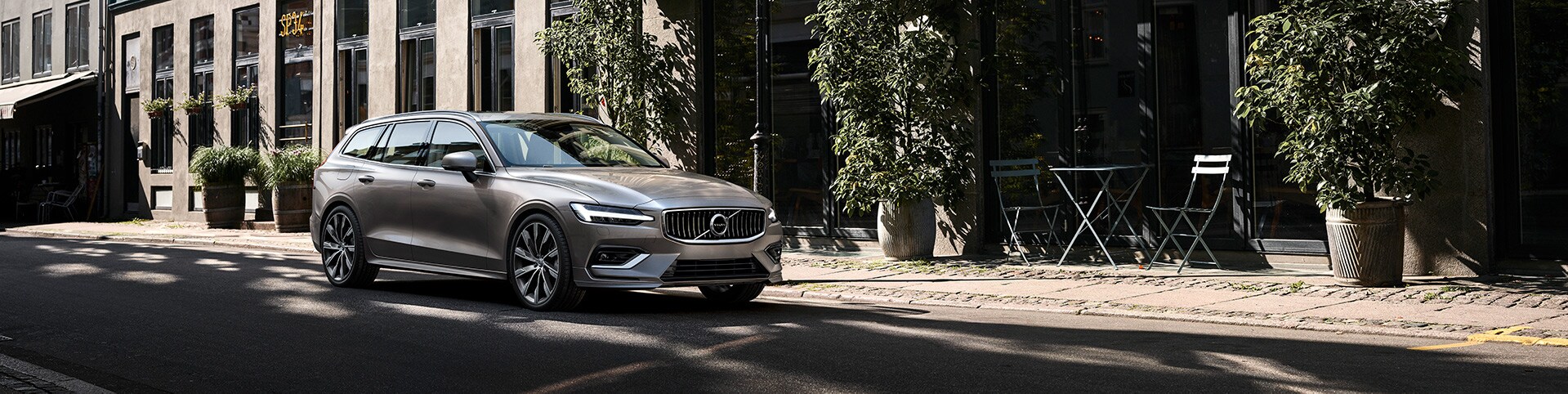 Volvo Cars New Bern is a Car Dealership near Oriental NC | Silver MY20 Volvo V60 parked in front of city building