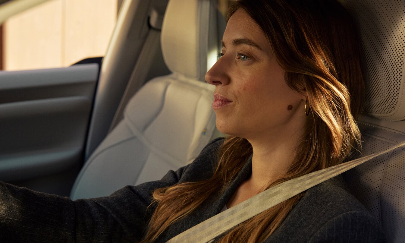 Close-up shot of a woman driving an EX60 seen from outside the driver side window.