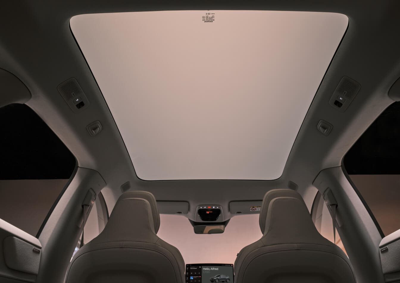 Low-angle interior view of a beige Volvo EX60 showing the panoramic glass roof.