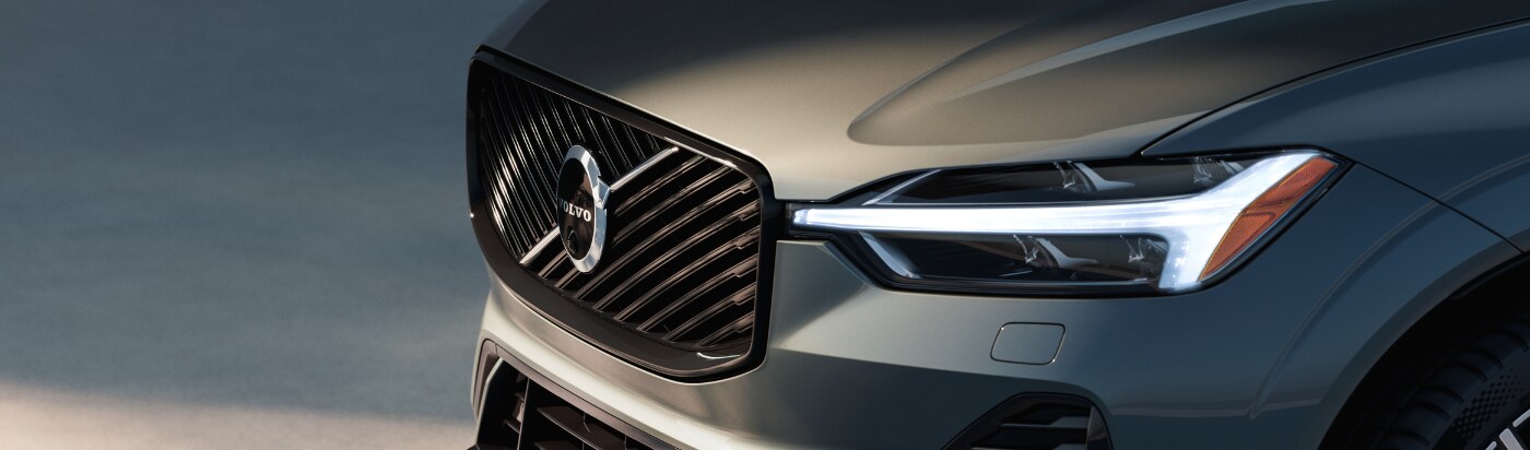 Close up photo of the front exterior of a 2025 Volvo XC60 Recharge. The SUV is gray and the Volvo logo is visible on the front grille