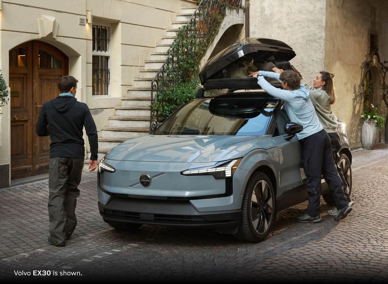 Volvo EX30 is shown on a brick driveway of a residence with people packing for a road trip.