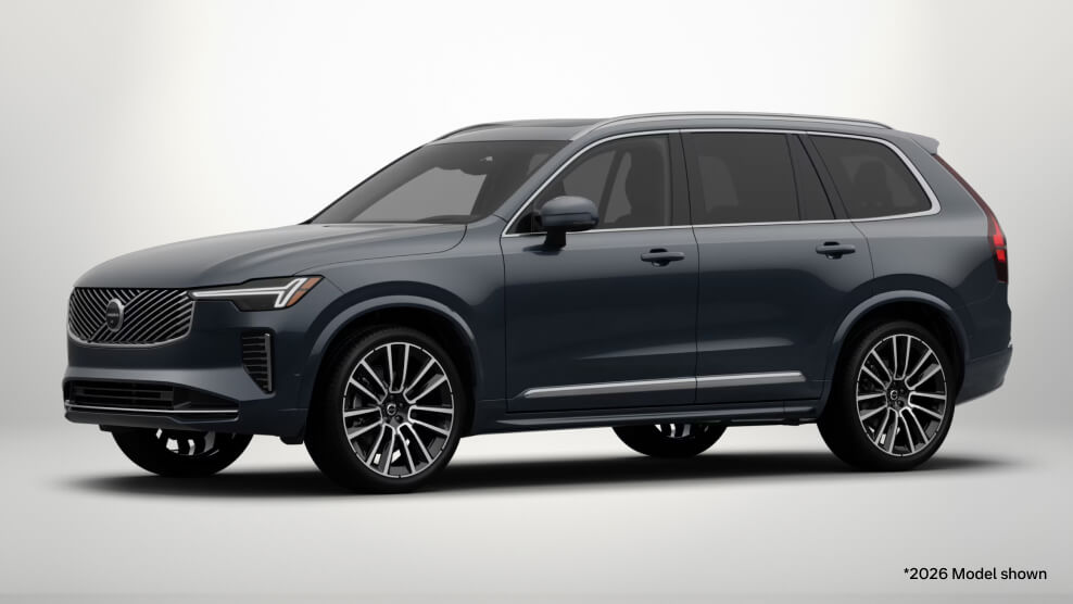 2026 Volvo XC90 Ultra in Denim Blue, front three-quarter view with a light gray studio background.