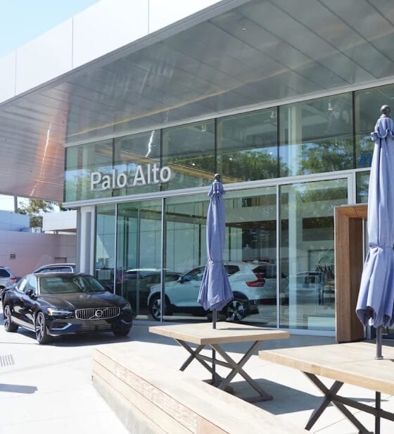 Front three-quarter view of a black Volvo S60 sedan outside the Volvo Palo Alto dealership patio.