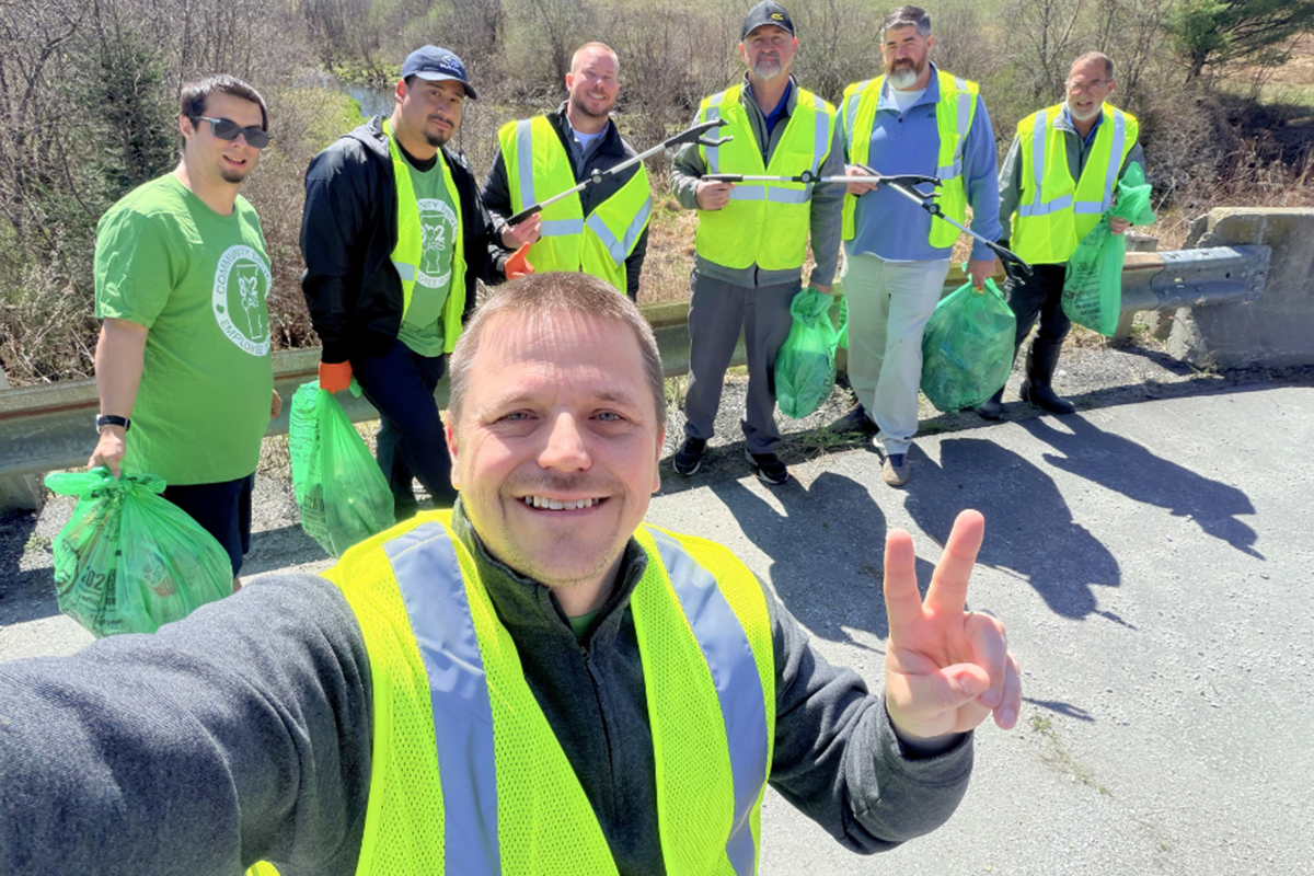 A group of dealership employees picking up trash along the road during a community service event 