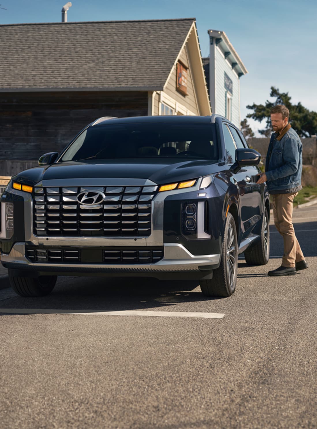 All-New 2023 Hyundai Palisade at West Broad Hyundai | Man unlocking his navy blue Hyundai Palisade car that is parked on the side of the road 