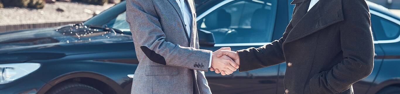 Best Time To Buy At  West Broad Hyundai in Henrico, VA | Man on the left is shaking hands with another man on the right wearing a black jacket, all while there is a black sedan behind them
