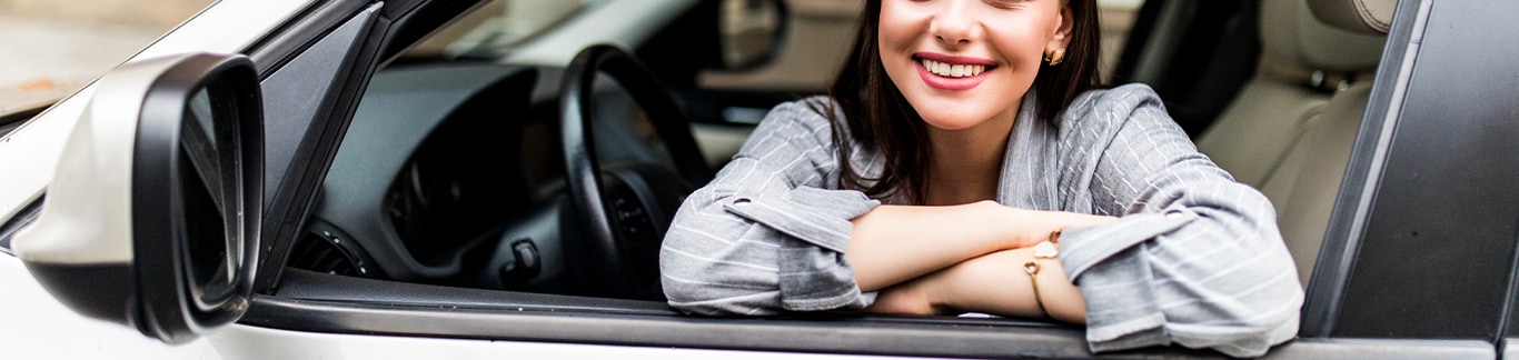 Best Time To Buy At  West Broad Hyundai in Henrico, VA | Woman in grey shirt is smiling while sitting in the drivers seat of her car 