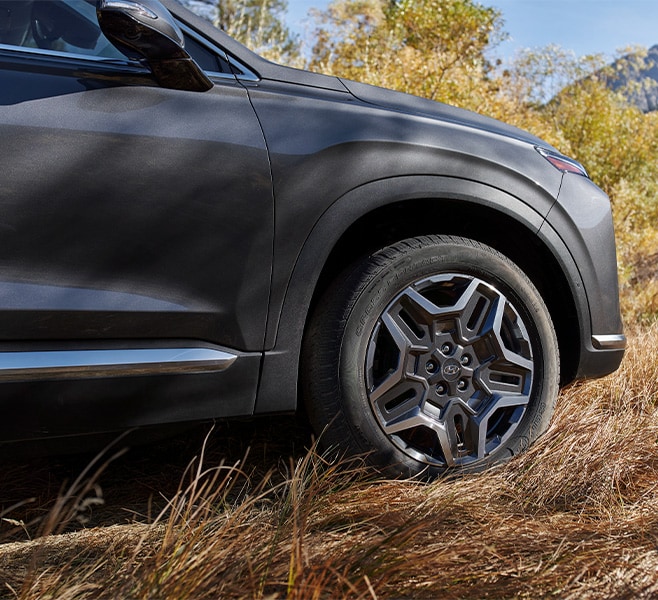 All-New 2022 Santa Fe Plug-in Hybrid at West Broad Hyundai | Close-Up Shot of Tire of the 2022 Hyundai Santa Fe PHEV Driving Over Brown Grass