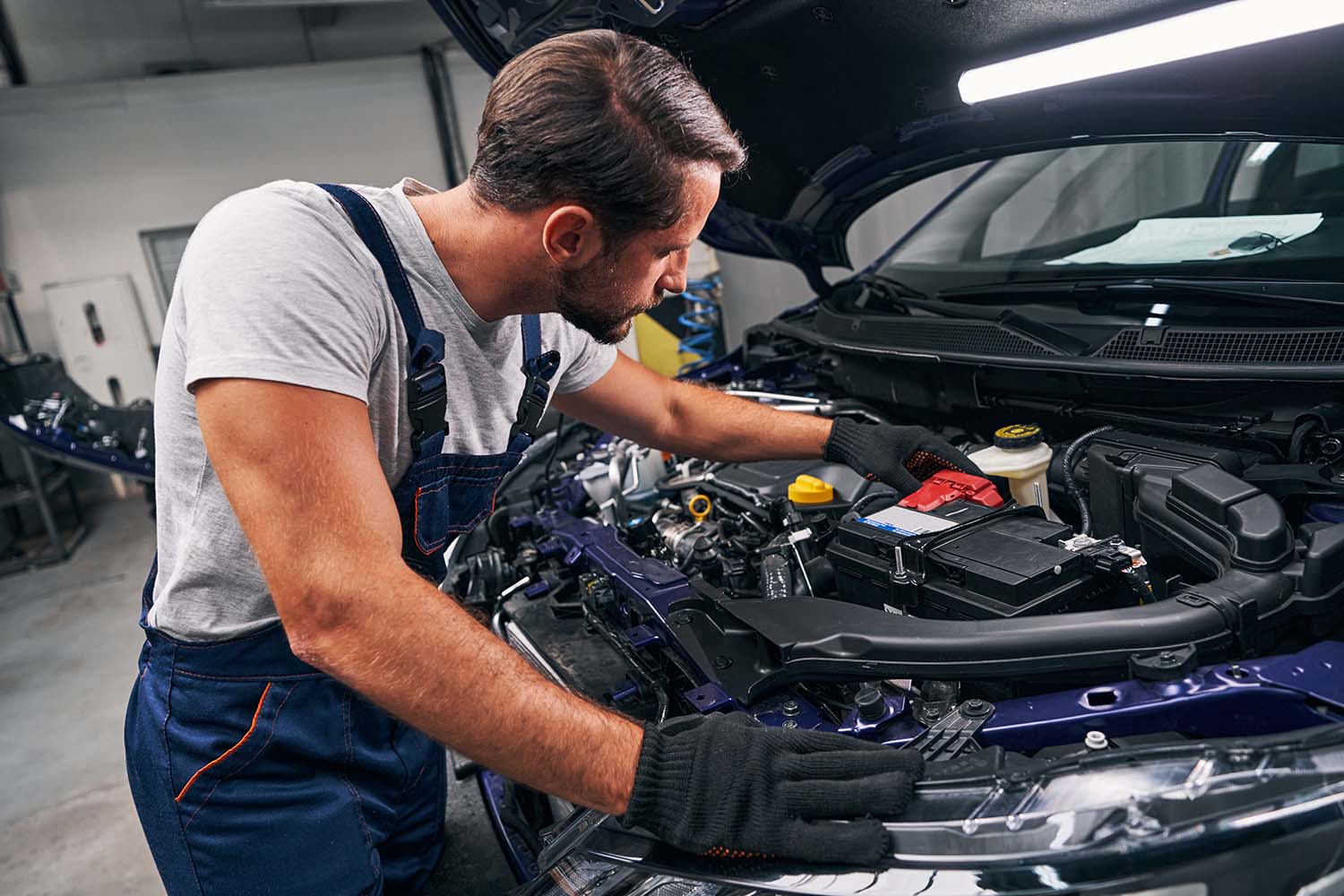 Everything You Need to Know about Your Car Battery at West Broad Kia | Kia service technician replacing a battery in a vehicle