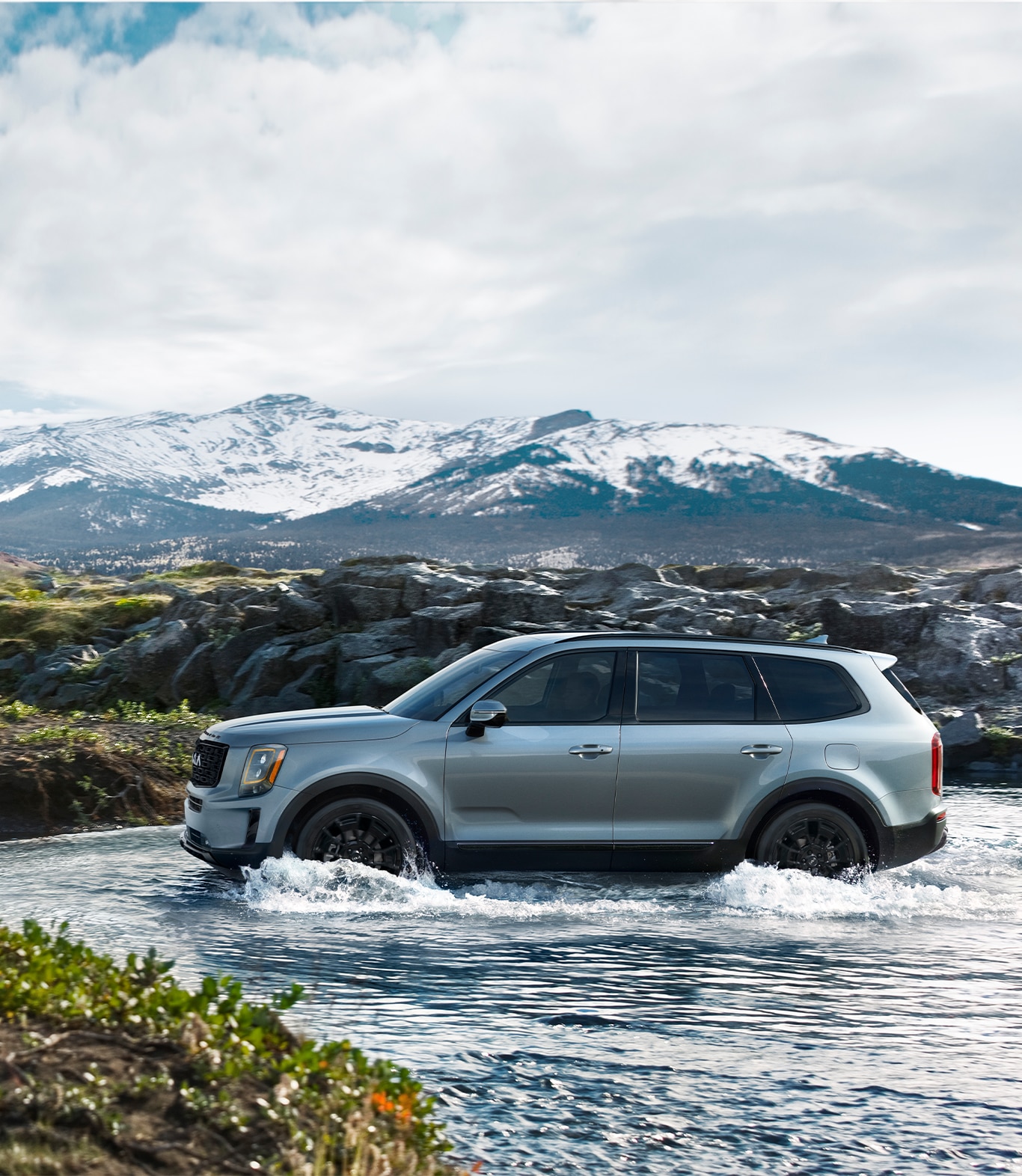 2023 Kia Telluride at West Broad Kia in Henrico, VA | Silver 2023 Kia Telluride driving over water with  mountains in the background 