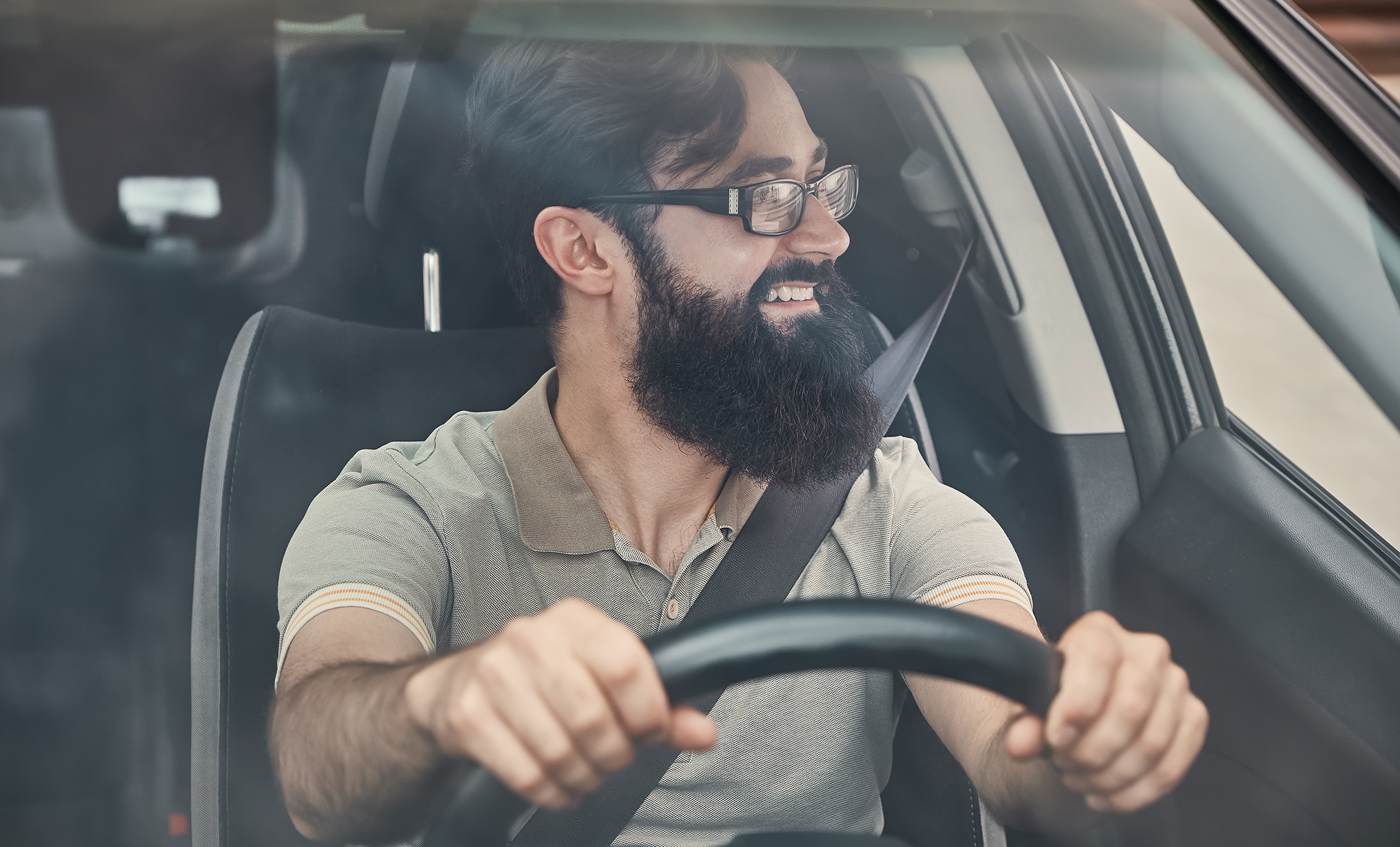 Why You Shouldn’t Drive Around with a Chipped Windshield at West Broad Kia in Richmond, VA | Happy guy driving while looking to his left