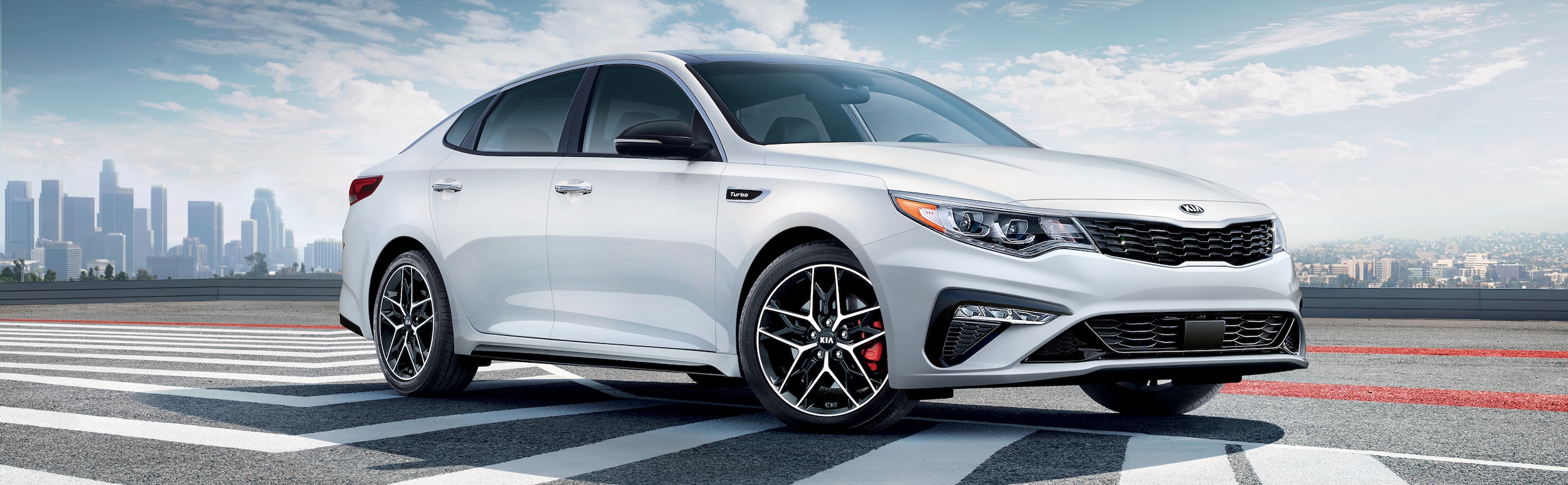 West Broad Kia is a Kia Dealership in Richmond, VA | 2020 Kia Optima driving on highway with city in distance