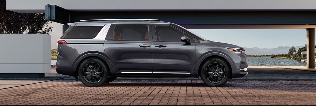 Model Features of the 2022 Kia Carnival at West Broad Kia | Kia Carnival parked at modern home