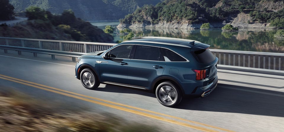 Tips for spring cleaning your car at West Broad Kia in Richmond, VA | Blue Kia Sorento HEV EX Driving Across Bridge Over a River in Mountains