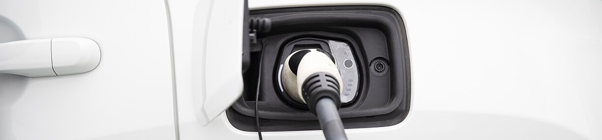 How to prepare your home for your new Electric Vehicle at West Broad Kia in Henrico, VA | Close up of a white electric charging cable connected to port, charging a white electric vehicle  