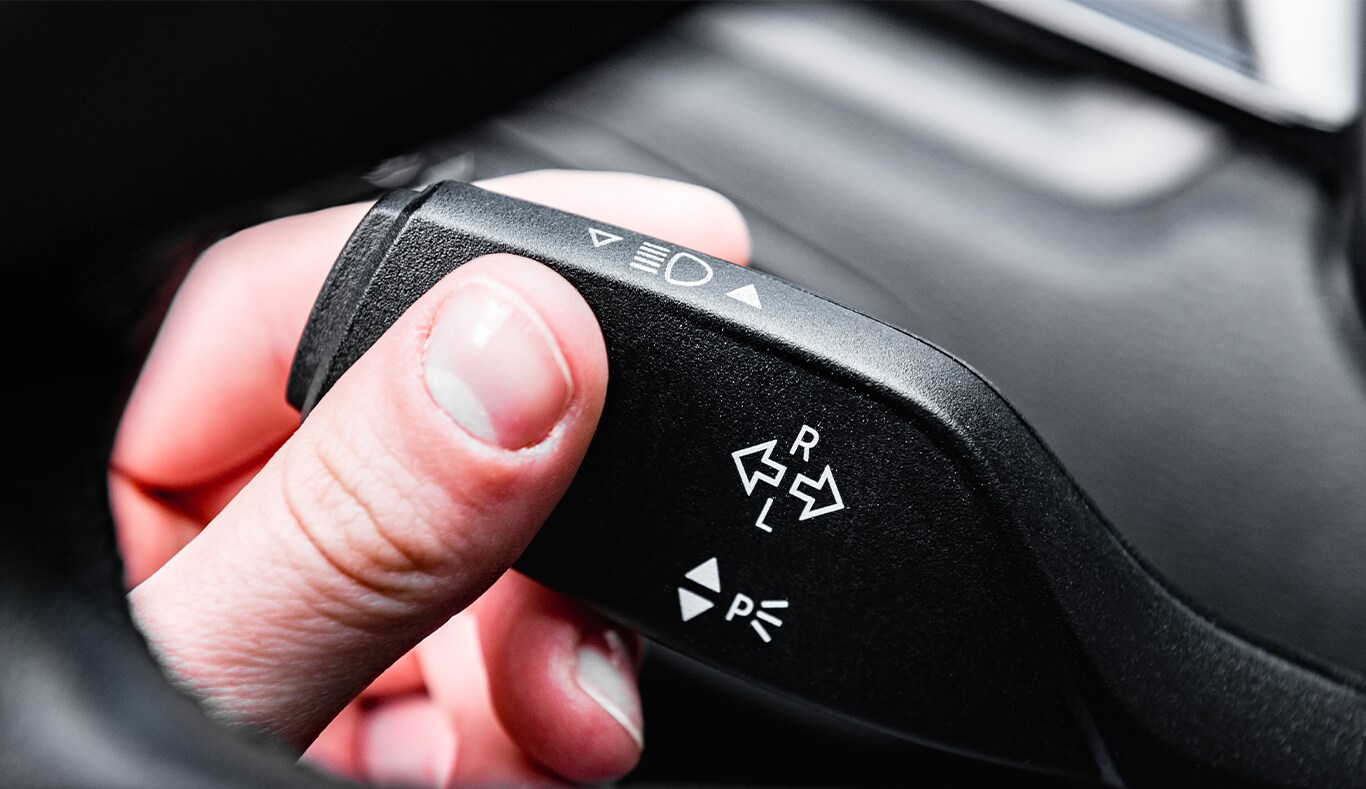 Understanding Your Kia’s Emergency Lights at West Broad Kia in Henrico, VA | Person's hand on signal indicator switch located beside steering wheel