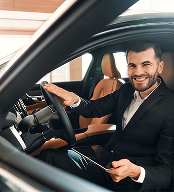 Defining GAP Insurance at West Broad Kia in Henrico, VA | Smiling man in black suit sitting in his new car