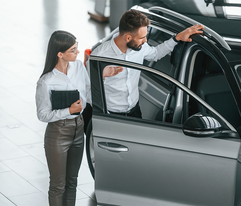 Why drivers should consider an extended warranty on their Kia at West Broad Kia | Customer checking out the passenger side of a new car 