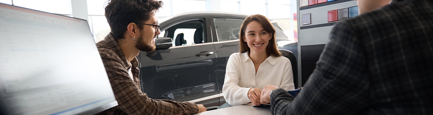 Defining GAP Insurance at West Broad Kia in Henrico, VA | Man and woman talking to car sales person at his desk 