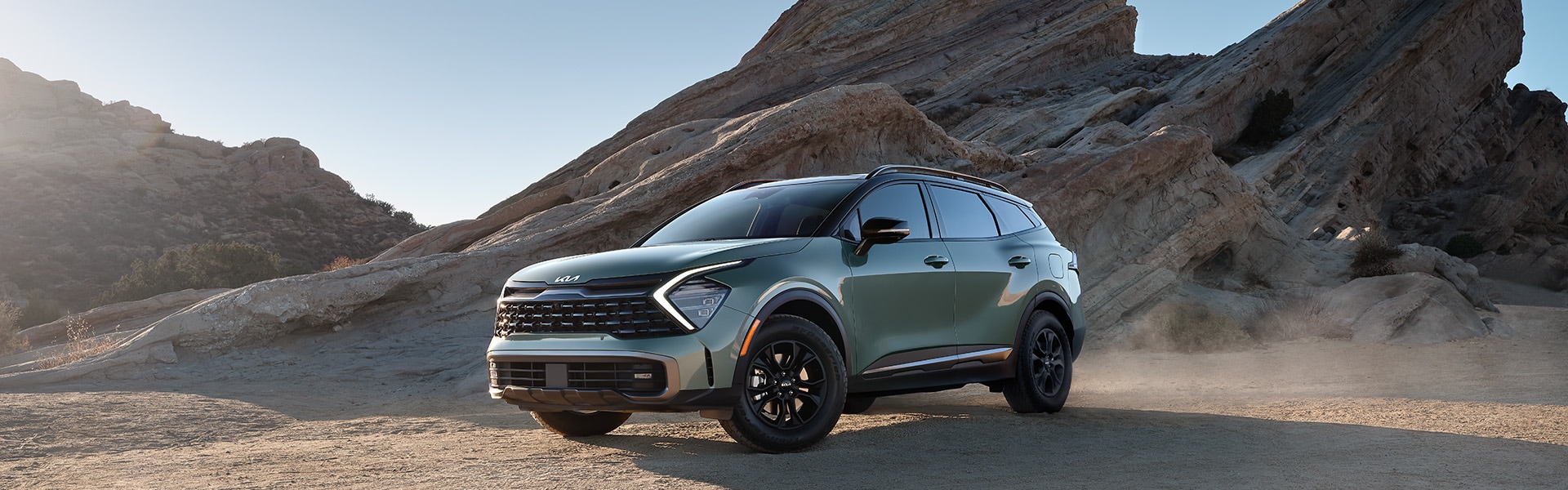 The All-New 2023 Kia Sportage at West Broad Kia in Henrico, VA | Green 2023 Kia Sportage Vehicles Parked in Desert in Front of Rock Formation