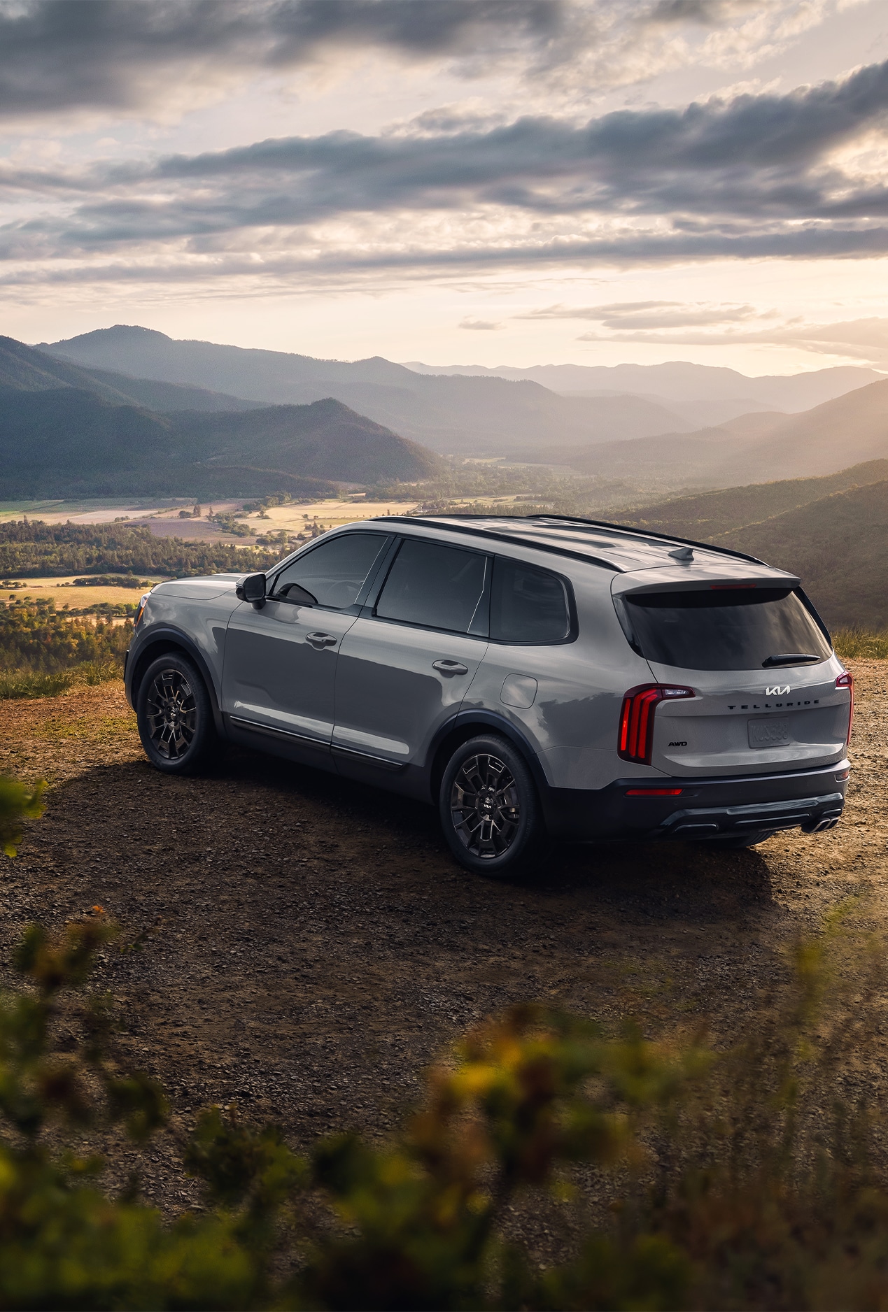 2023 Kia Telluride at West Broad Kia in Henrico, VA | Rear view of a Silver 2023 Kia Telluride parked on a dirt road with mountains in the background