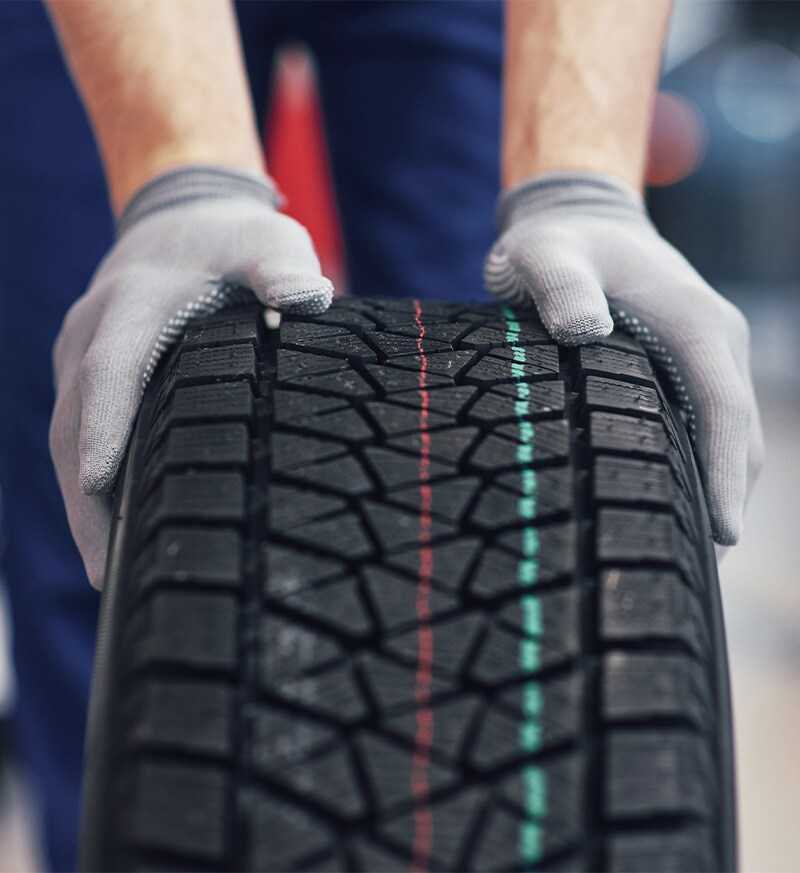 what different tire options are available at West Broad Kia in Richmond | Service Advisor Rolling Tire on Floor of Service Bay