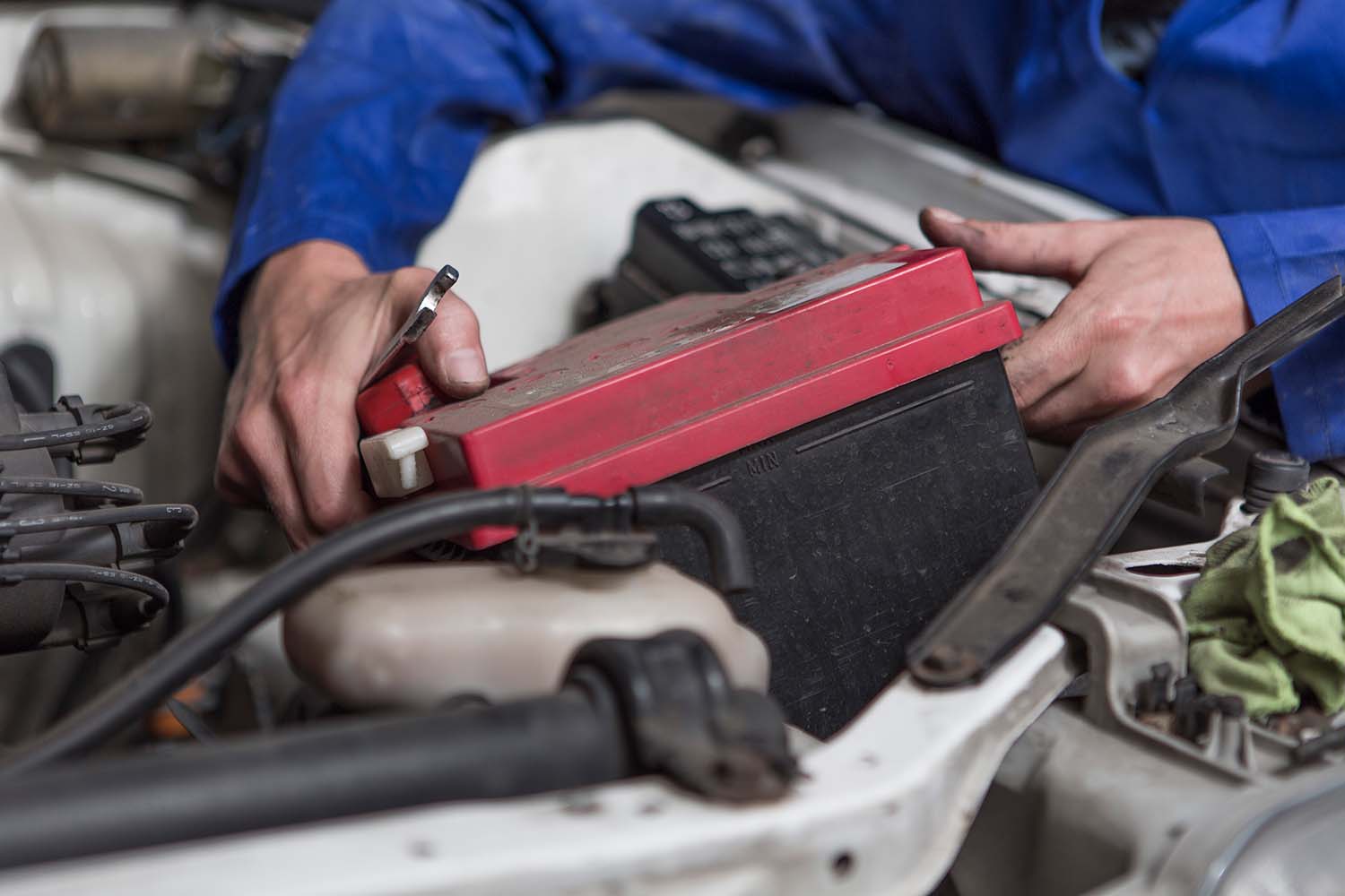 Everything You Need to Know about Your Car Battery at West Broad Kia | Mechanic taking old battery out of vehicle to put a new one in