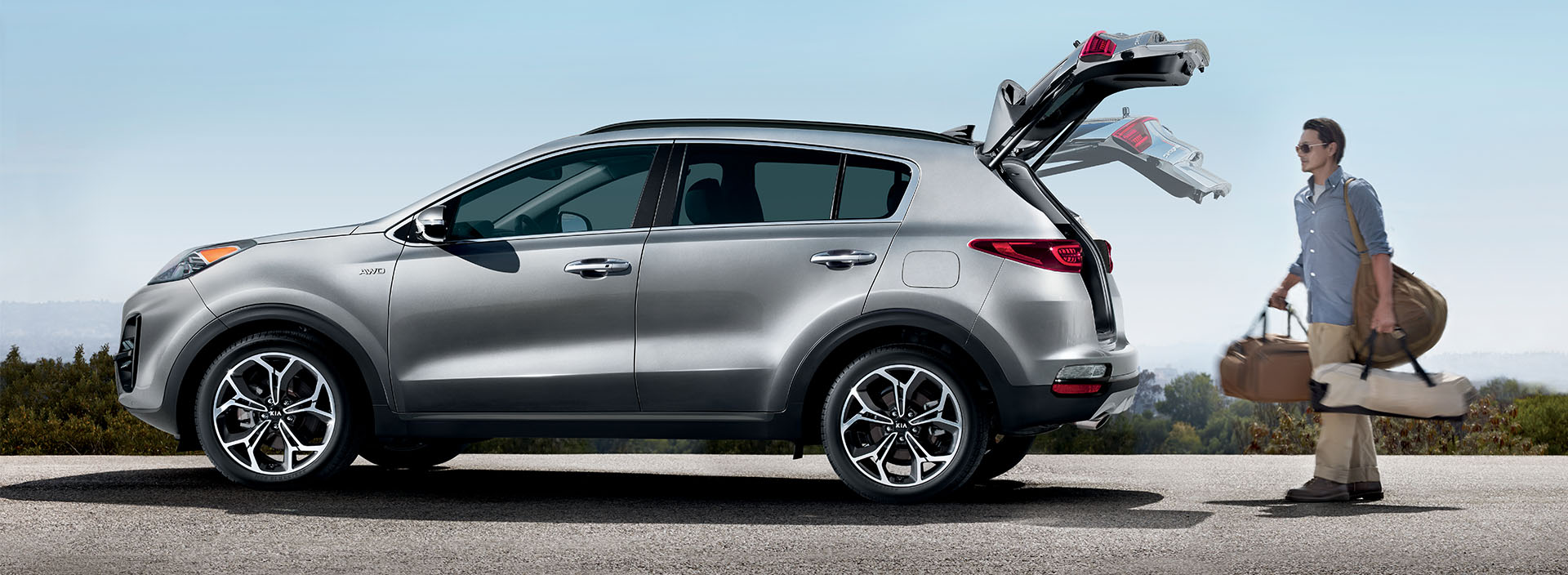 Accessories that help keep your Kia protected at West Broad Kia in Richmond, VA | Man Carrying Bags to Open Trunk of Kia Sportage SX AWD