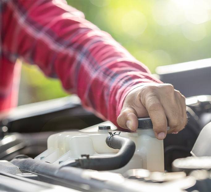 How to Get Your Car Summer Ready at West Broad VW in Richmond, VA | Man in red checker shirt opening the lid to a radiator reservoir