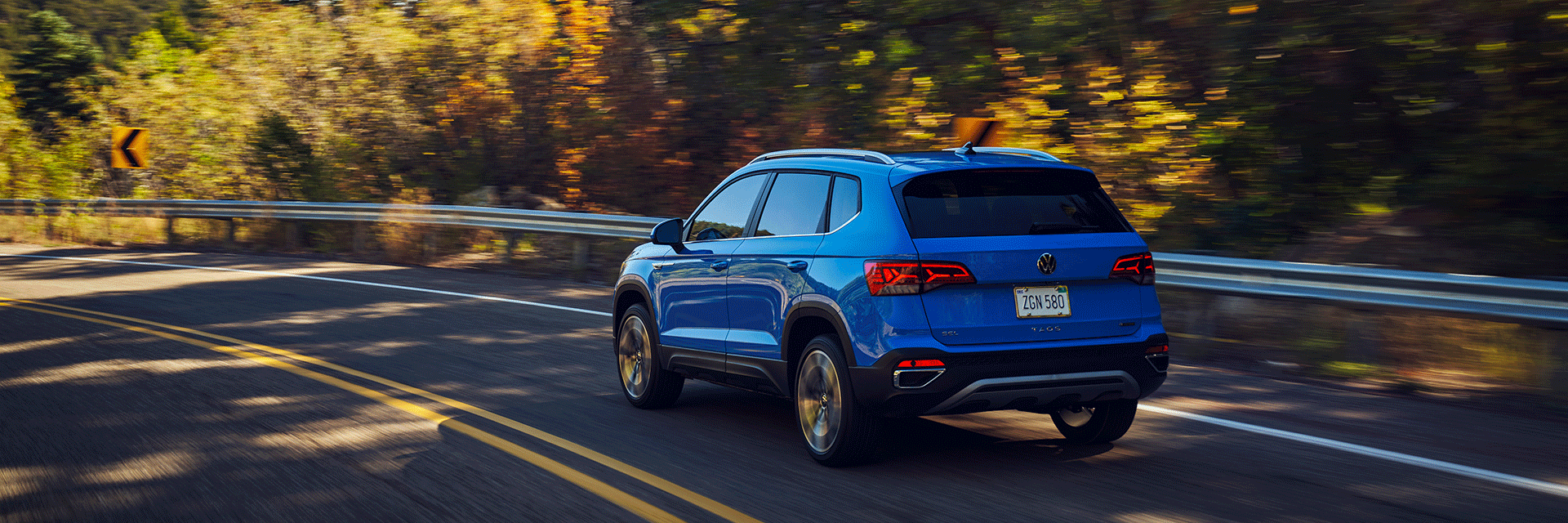 Things to Check When Buying a Used Car | West Broad Volkswagen in Richmond, VA | Blue 2022 Volkswagen Taos Driving on Road with Guardrailing Surrounded by Trees