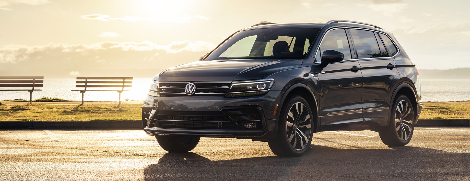 Compare the 2021 Volkswagen Tiguan vs. the 2021 Honda CR-V at West Broad Volkswagen | Dark Gray 2021 Volkswagen Tiguan Parked by Water at Sunset