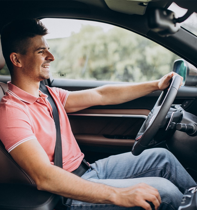 Extend the Life of Your Vehicle at West Broad VW in Richmond, VA | Man in pink polo shirt is smiling while driving his car with one hand on the steering wheel 
