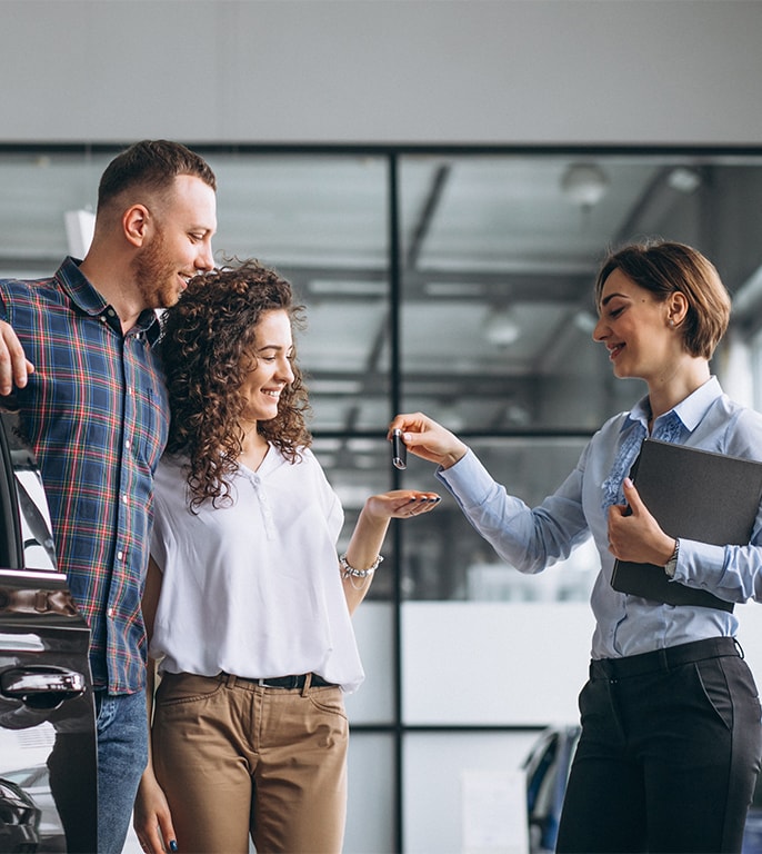When to Trade In Your Car | West Broad VW in Richmond, VA | Salesperson holding a folder on the right side is handing over keys to the couple on the left side 