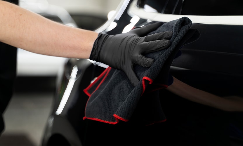 Extend the Life of Your Vehicle at West Broad VW in Richmond, VA | Person with black gloves wiping car exterior with black microfiber towel  