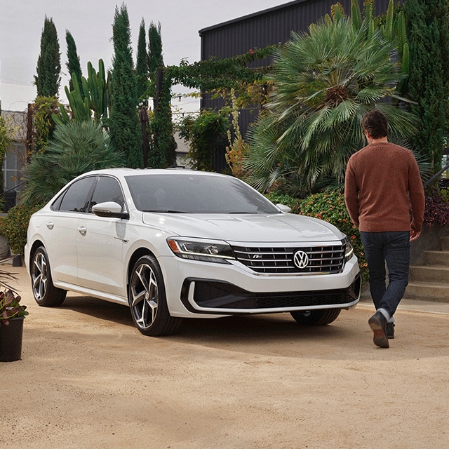 Things to Check When Buying a Used Car | West Broad Volkswagen in Richmond, VA | Man Walking Around Front of Parked 2021 White Volkswagen Passat Facing Right