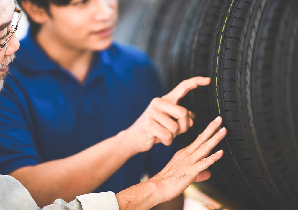 Learn Maintenance Warning Signs at West Broad VW in Richmond, VA | Two men are checking the thread of new car tires