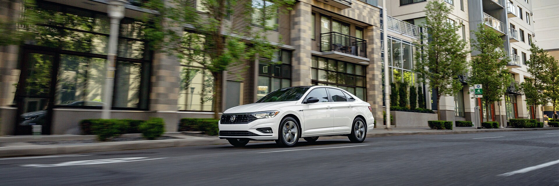 Things to Check When Buying a Used Car | West Broad Volkswagen in Richmond, VA | White 2021 Volkswagen Jetta Facing Left Driving on Road in City with Trees Lining Sidewalks
