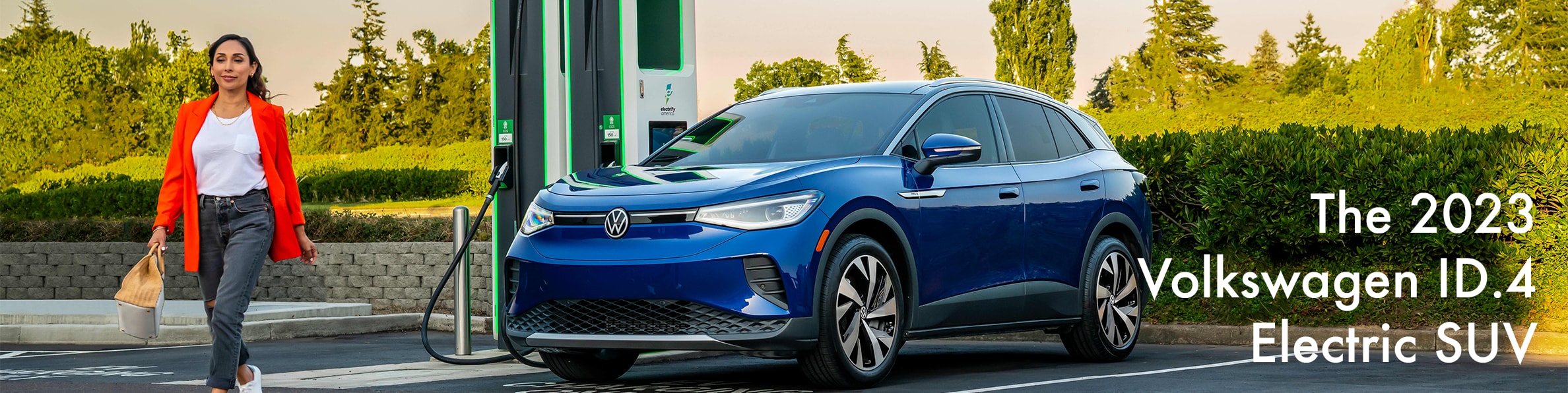 2023 ID.4 Electric SUV at West Broad VW | Navy blue 2023 parked next to car charger with a woman in orange blazer walking away from it 