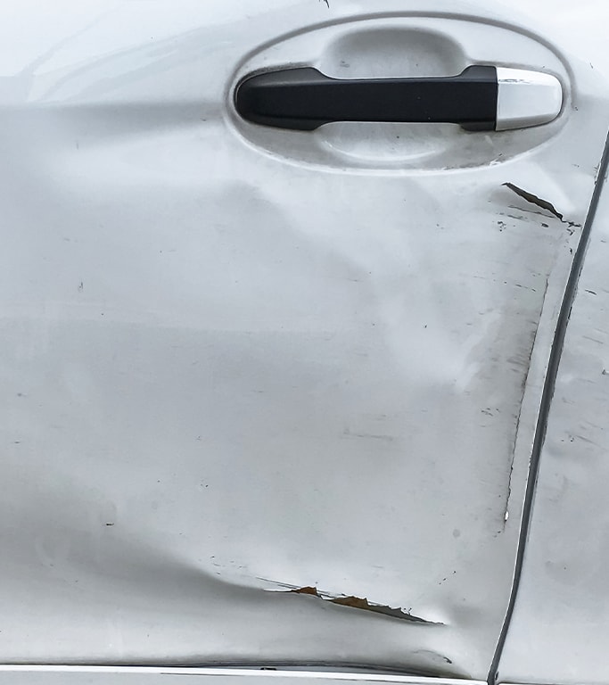 What is Paintless Dent Repair? | West Broad VW | White car door with a big dent and paint chip