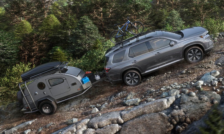 2025 Honda Pilot towing a camper up a mountain