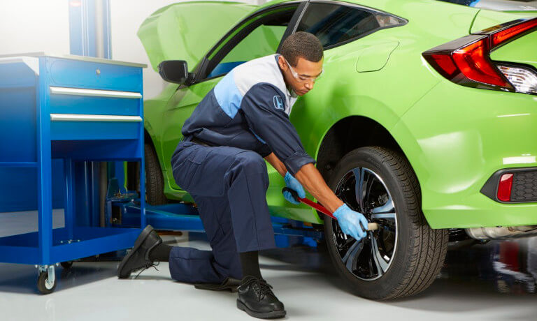 Honda-Service-MechanicWithWrenchRemovingWheel