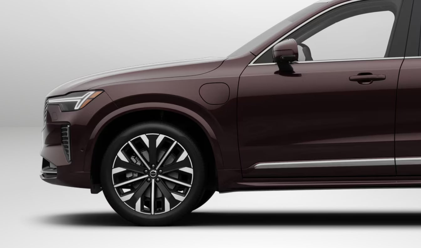 Side view of a 2026 Volvo XC90 SUV shown in Mulberry Red against a white background, focusing on the front half.