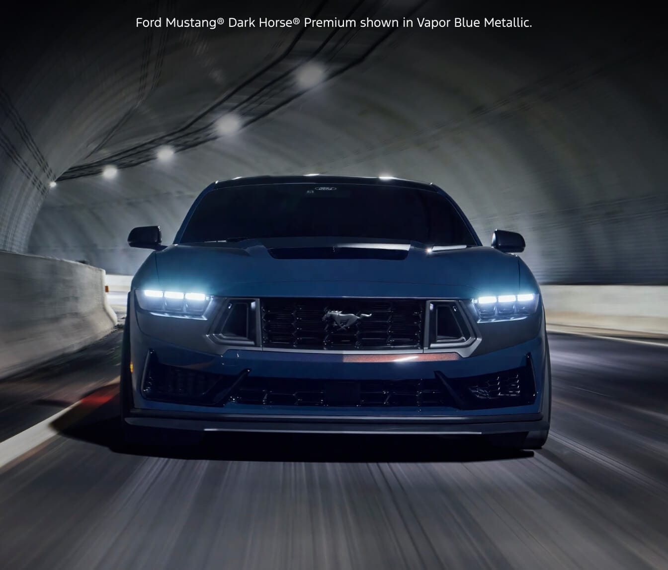 Direct front head-on shot of a 2026 Ford Mustang Dark Horse Premium in Vapor Blue Metallic driving through an illuminated tunnel.
