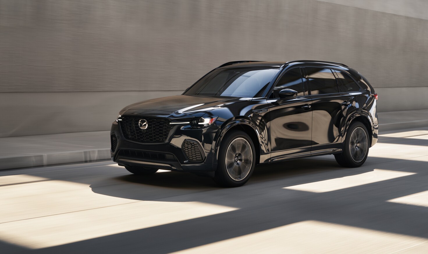 Black Mazda CX-70 SUV driving on the highway, available through Woodhouse Place Mazda in Omaha.