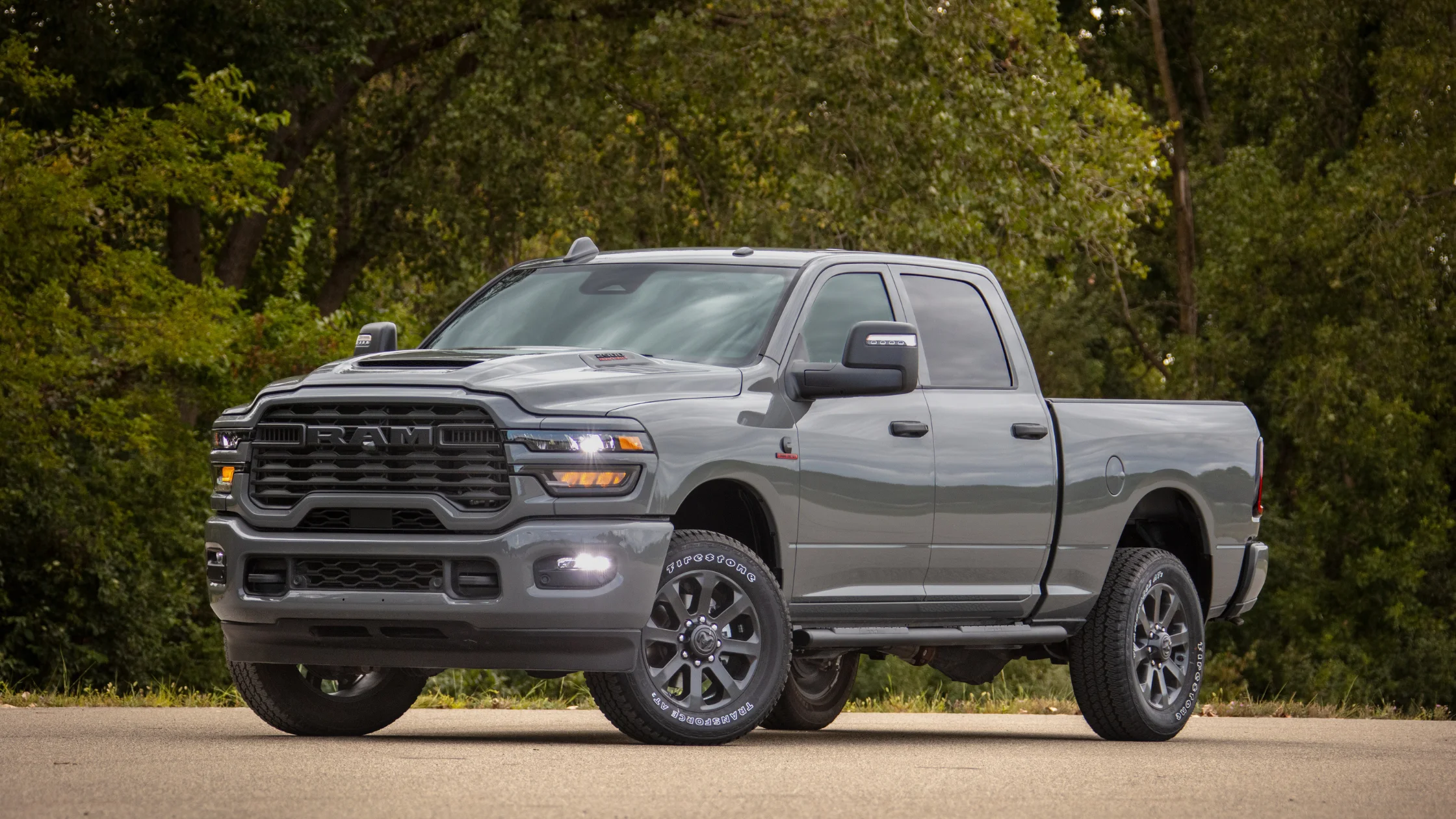 2026 Ram Heavy Duty gray crew cab pickup parked by trees with bold grille and work-ready stance