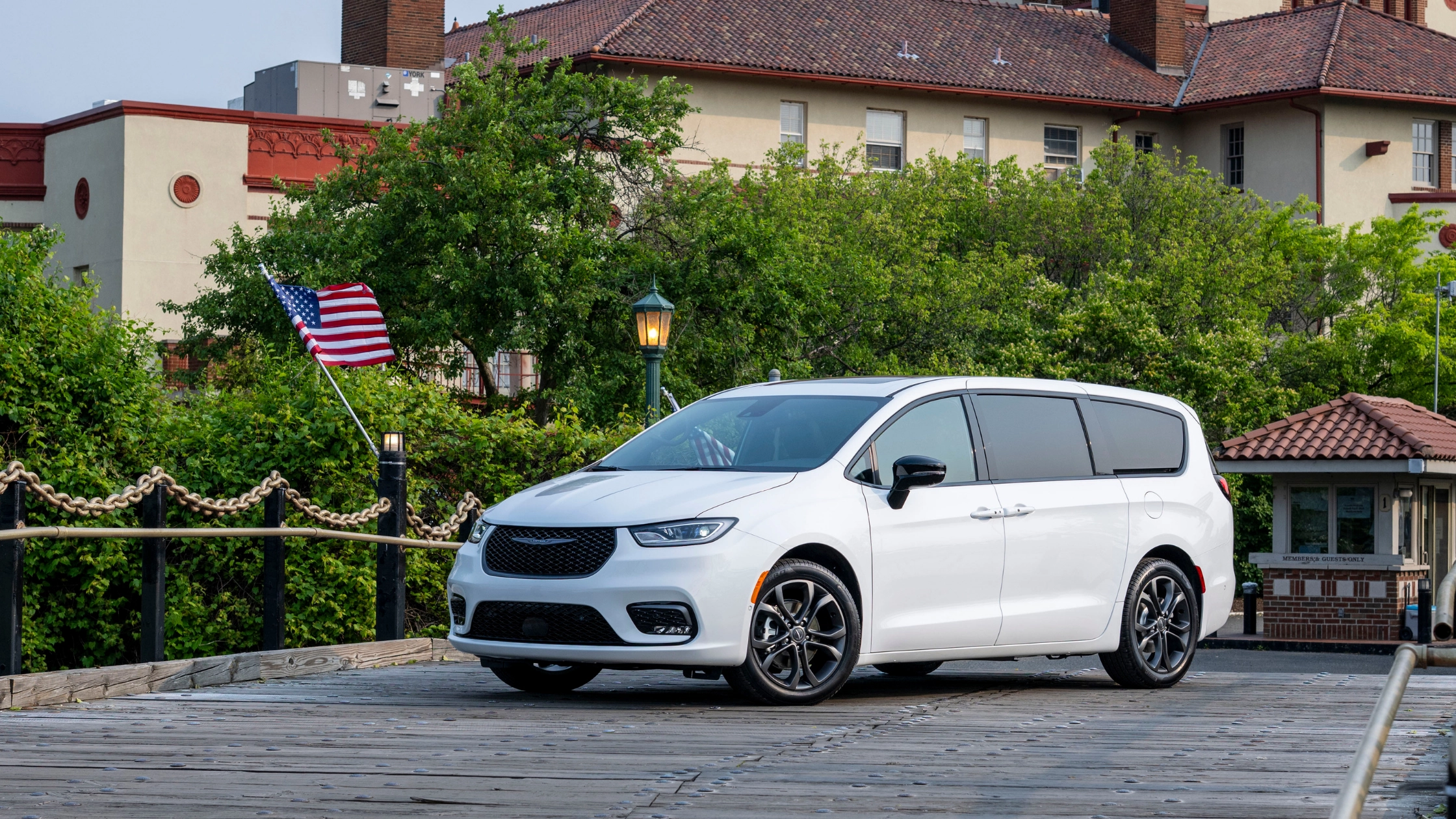 2026 Chrysler Pacifica white minivan parked on bridge with greenery and American flag
