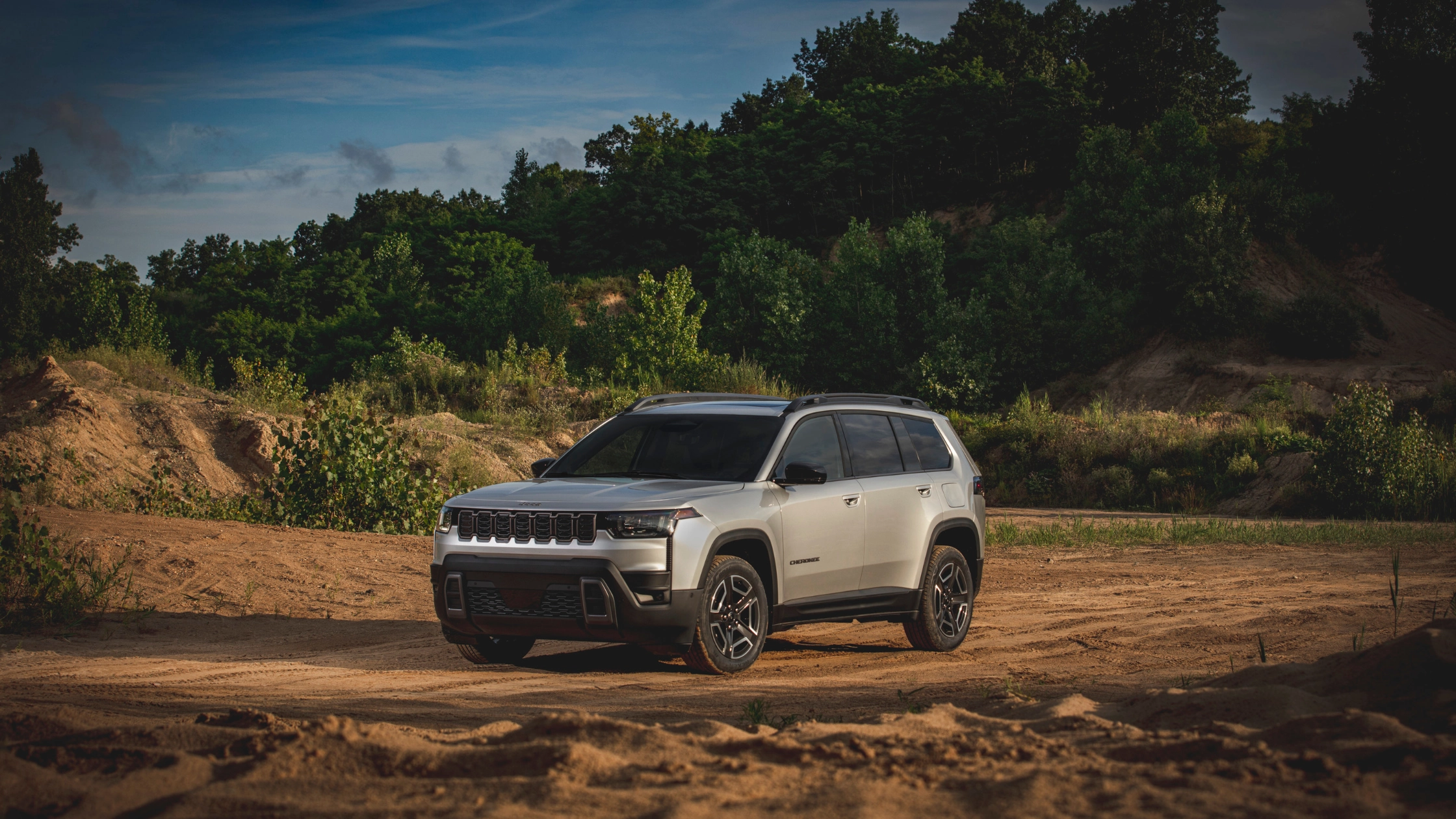 2026 Jeep® Cherokee white SUV on dirt trail with rugged wheels and wooded background