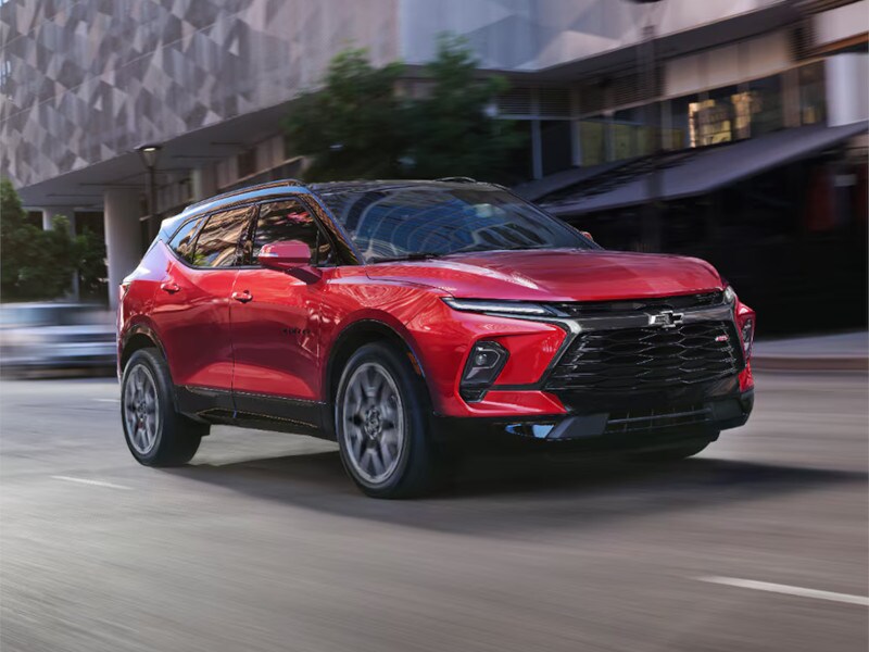 A 2026 Chevrolet Blazer driving along a bustling city street, showcasing its sleek design and urban environment.