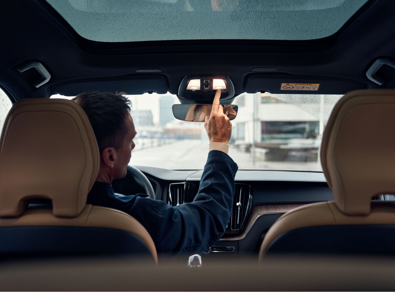 Rear interior view of a Volvo XC60 in Amber Nappa Leather with a driver using the console light.